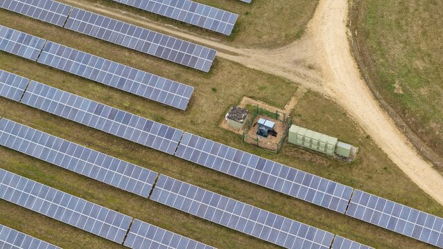 Aerial view of sun-drenched solar farm panels stretch across the landscape near the former RAF Alconbury, Huntingdon, Cambridgeshire, United Kingdom.