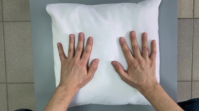 Pillow. White pillow. Male hands. Table. Slow motion video. High quality 4k footage