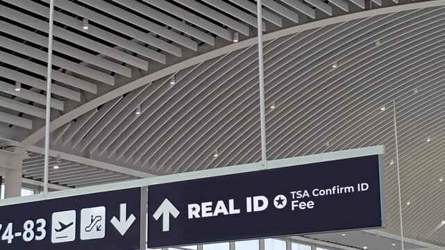 Airport overhead sign directing passengers to REAL ID compliance and TSA Confirm ID Fee