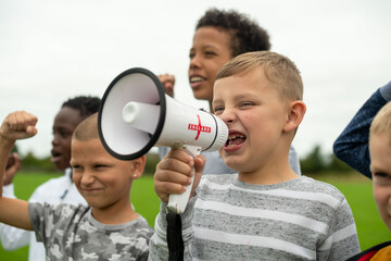 Children shouting with megaphone outdoors.