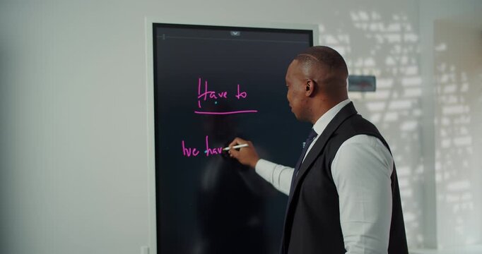 Businessman writing modal verb notes on digital board during presentation