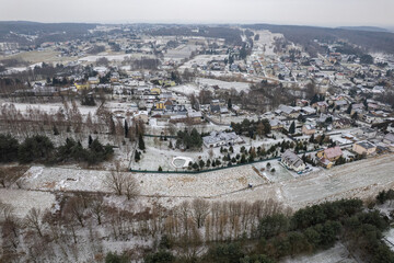 Obraz premium Aerial landscape of a peaceful village surrounded by fields and forests in winter season