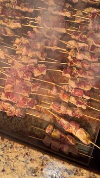 Beef Meat Kebabs Espetada on Wooden Skewers Roasting on a Steaming Hot BBQ Grill