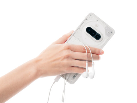 Dnipro, Ukraine, April 29, 2025: A hand holding a Nothing Phone (3a) smartphone and Apple EarPods. Wired headphones. Music.