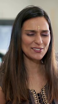 Vertical video: Smiling woman with bindi and embroidered top responding to offscreen voice at home