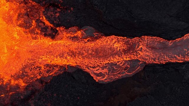 Aerial view of a river of molten lava snaking through a dark, rocky landscape, a vibrant display of nature's raw power, Grindavik, Grindavikurbaer, Iceland.