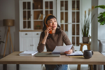 Woman working remotely making phone call reading document