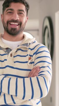 Vertical video: Framing shift, smiling man in striped sweater moving left in hall, revealing mirror