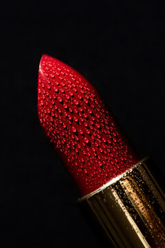 Red lipstick on black background with droplets