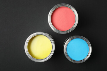 Can of bright paint and brush on black background, top view
