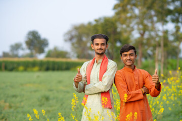 Naklejka premium two young indian farmer standing together at field