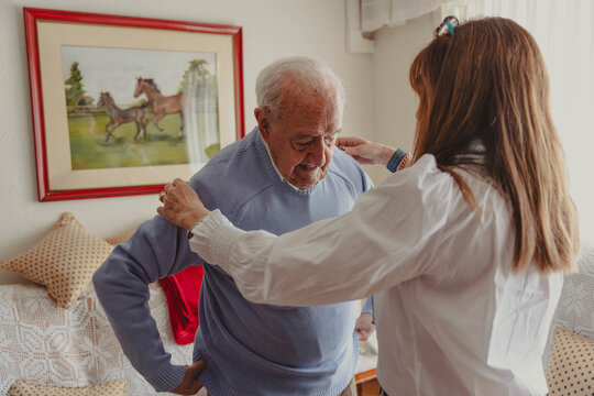 Daughter assisting senior man with dressing at home