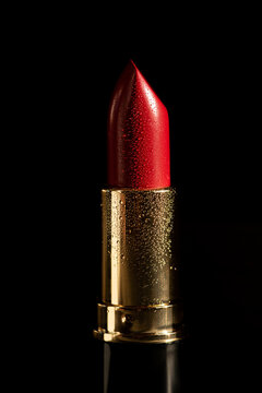 Red lipstick on black background with droplets