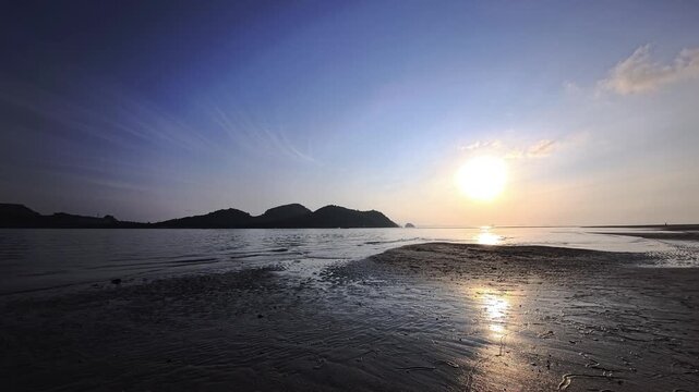 Wide coastal sandbar with sun reflection and distant islands Thailand