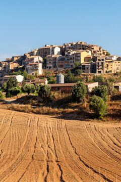 Hillside village overlooking farmland furrows in Terra Alta Catalonia Spain showing agriculture landscape structure with rural countryside feel