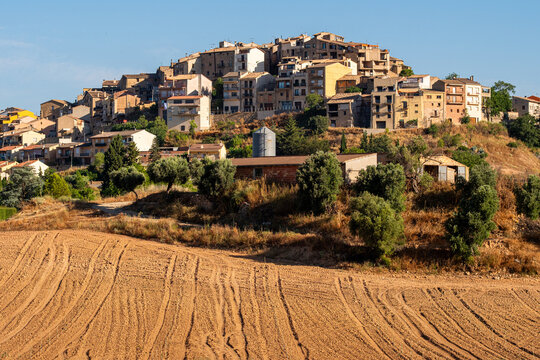 Hillside village beside farmland fields and furrows in Terra Alta Catalonia Spain showing rural agriculture landscape depth and soil patterns