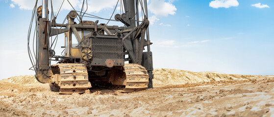 A pile driving rig is at work on a construction site, driving piles into the ground to support...