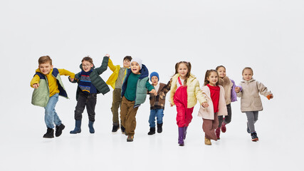 Obraz premium Children running toward camera wearing colorful kids outfits in studio. Concept of playful childhood movement, modern kids clothing and energetic fashion campaign.