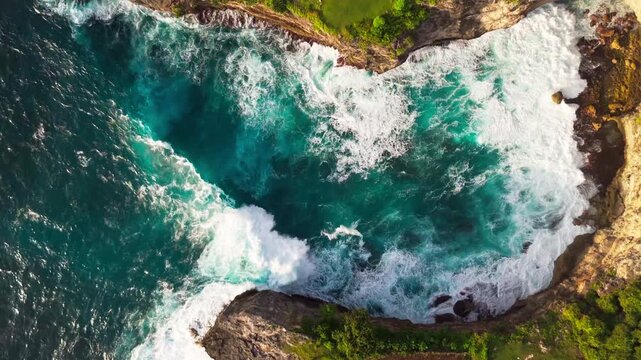 Cinematic aerial top-down of Devil's Billabong &ndash; Powerful ocean waves crashing into rocky tide pools and limestone cliffs in Nusa Penida, Bali