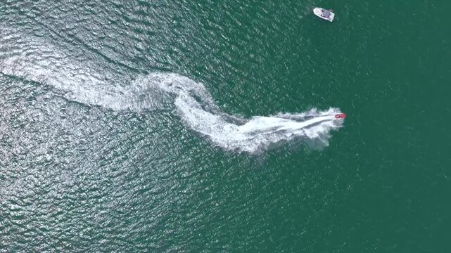 Aerial view of a lone boat speeding across the ocean, leaving a trail of white foam against the dark green waters, Punta del Este, Maldonado Department, Uruguay.