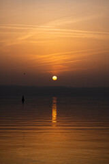 Golden sunset over a calm lake with sun reflection