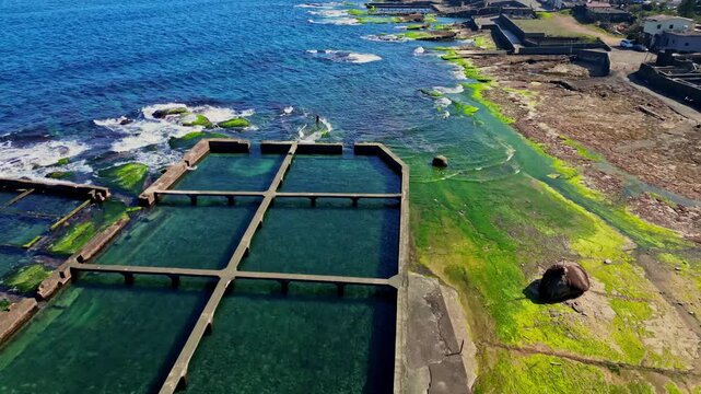 Aerial view of aquaculture with vibrant green algae contrasting against the deep blue sea, creating a striking visual, New Taipei City, Taiwan.