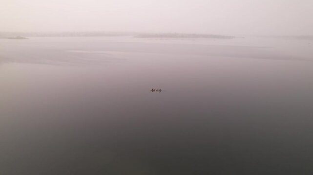 Aerial view of a boat sailing on the water, the pale sky creating a muted, ethereal tone over the scene, Suleja, Niger, Nigeria.