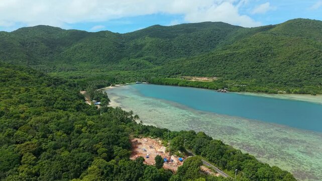 Aerial view of lush green mountains meeting turquoise waters, showcasing the natural beauty of the coastline, Karimunjawa, Central Java, Indonesia.