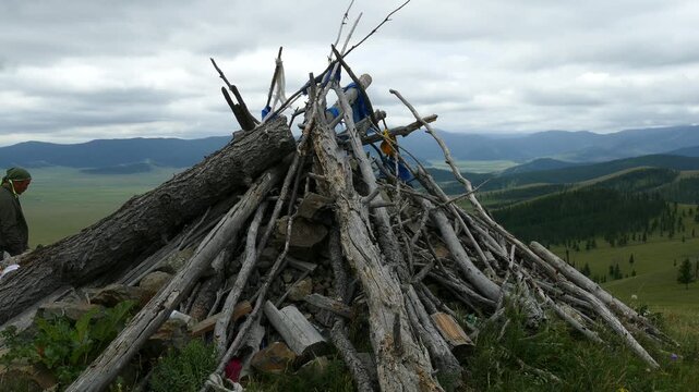 Obo (ovoo) is a sacred object in the form of a heap of stones and a hut of logs against the background of low, coniferous forests and picturesque cloudy skies. The Mongolian landscape.