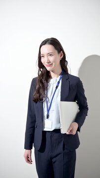 A woman in a business setting, seen from behind as she walks, then turning with a smile Vertical video showcasing career advancement, growth, success, and recruitment for working women