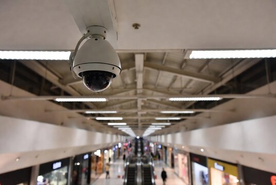 A security camera hangs in an underground mall corridor.