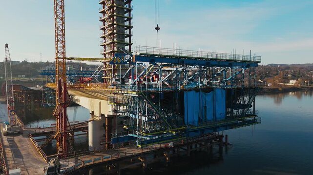 Aerial view of a bridge under construction with cranes and scaffolding over the water, contrasting with the clear sky, Novi Sad, Vojvodina, Serbia.
