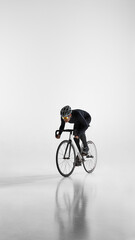 Naklejka premium Professional cyclist riding fast on road bike isolated on white. Concept of high speed performance, competitive cycling, athletic power, and sport motivation.
