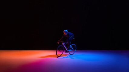 Fototapeta premium High speed cyclist on road bike in neon studio environment. Concept of advanced sports technology, fintech acceleration, insurance protection, brand performance and digital business growth.
