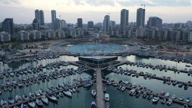 Aerial view of Ashdod Marina, where numerous boats rest in the calm water, set against the backdrop of the city's skyline, Ashdod, South District, Israel.