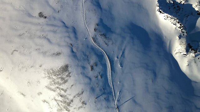Aerial view of the stark white snow-covered Hegafell mountain terrain, etched with a winding trail under a clear winter sky, Hafnarfjordur, Hafnarfjardarkaupstadur, Iceland.