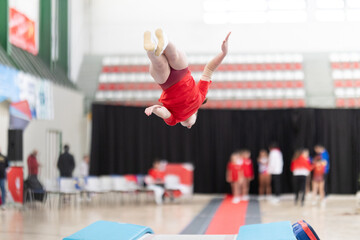 Obraz premium Gymnast performing somersault in indoor gymnastics competition