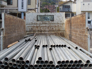 建設現場のダンプトラックに載っている建築材料や足場の鉄パイプ © kinomin