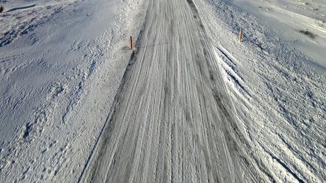 Aerial view of Krysuvikurvegur winter road, a stark contrast of dark rock and brilliant white snow, a winter wonderland landscape, Hafnarfjordur, Iceland.