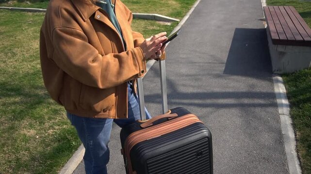 Woman is preparing to go to the airport with a suitcase, she checks the online scoreboard and check in time. Woman calls a taxi through a mobile application