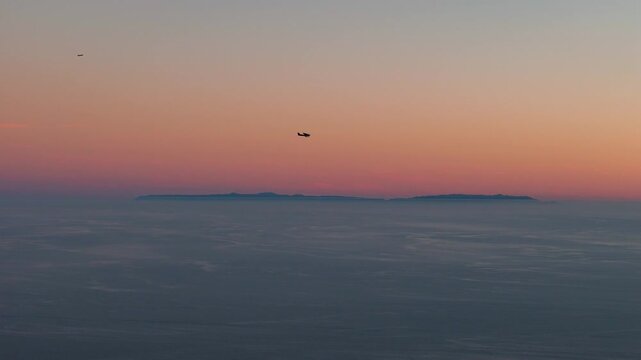 Aerial view of the Channel Islands shrouded in mist under a pastel sky at sunset, creating a serene yet ethereal seascape, Malibu, California, United States.
