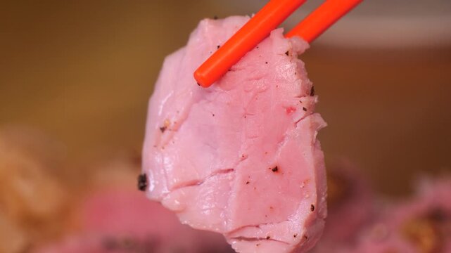 Pink piece of sous vide sirloin picked up with chopsticks