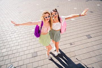 Girls on a sunny urban journey share laughs and style as best friends travel light backpacks...