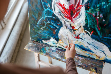 Close-up of female artist's hand painting with oil paints
