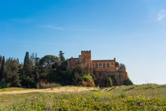 Historische Festung Castelo de S&atilde;o Jo&atilde;o do Arade auf einem Felsen bei Ferragudo, aufgenommen &uuml;ber eine Wiese in der typischen Landschaft der Algarve.