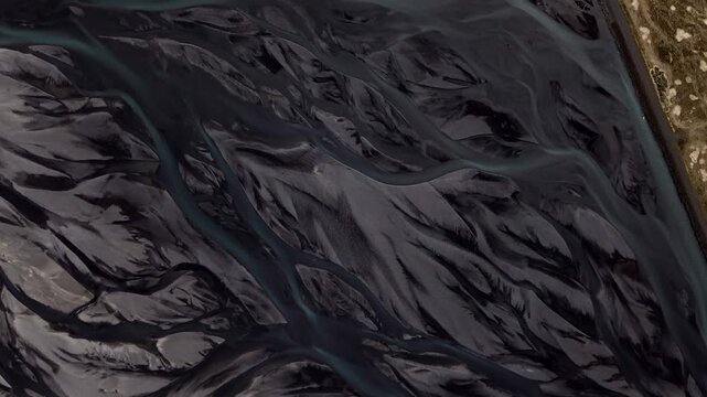 Aerial view of glacial rivers carving through volcanic sands, creating a mesmerizing tapestry of dark water and grey earth, Rangarthing eystra, Iceland.