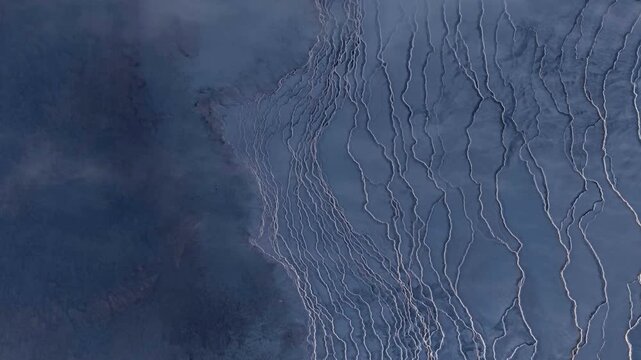 Aerial view of a landscape where the contrasting hues of dark terrain meet pale river systems, creating a stunning contrast, Grindavikurbaer, Iceland.