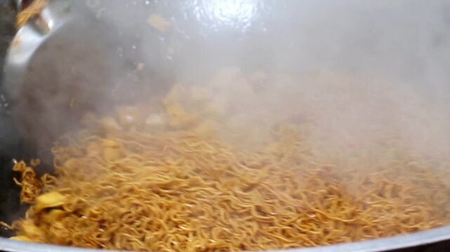 Close-up of professional chef hand tossing noodles and tofu in a sizzling wok at a Thailand night market. Capturing the aromatic steam and wok hei essence for food lifestyle content.