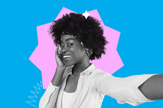 A woman smiles while taking a selfie. She wears a headband and a light shirt. The background is bright with shapes and colors. She enjoys capturing this moment with her phone.