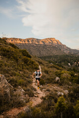 Obraz premium Athlete navigating a technical mountain trail while running through rugged natural terrain. Outdoor workout combining endurance, agility and adventure in wild landscape.